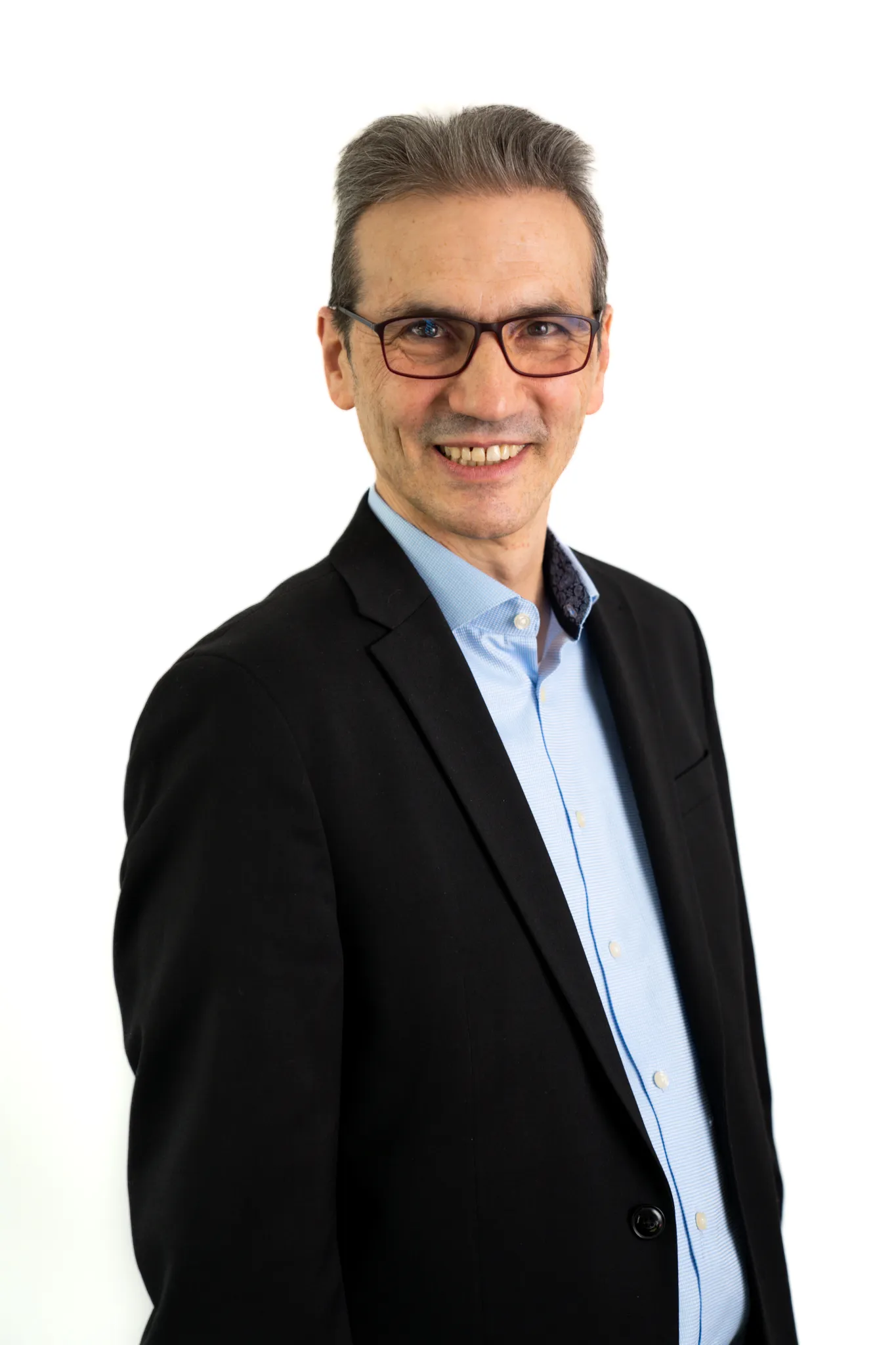 Porträt eines Mannes mit Brille im Anzug, der frontal in die Kamera lächelt.