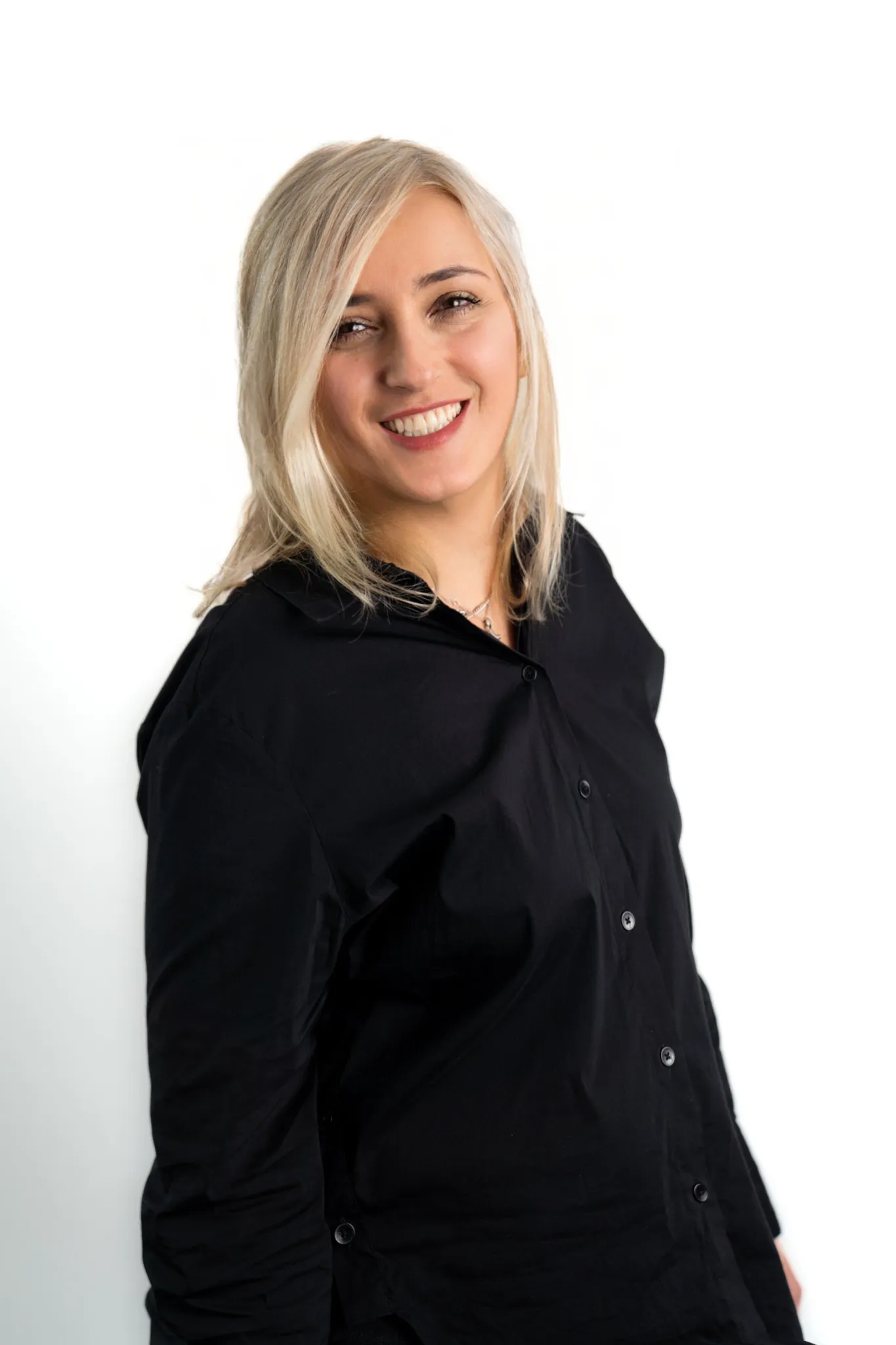 Porträt einer Frau mit hellblonden Haaren in schwarzer Bluse, die freundlich in die Kamera lächelt.