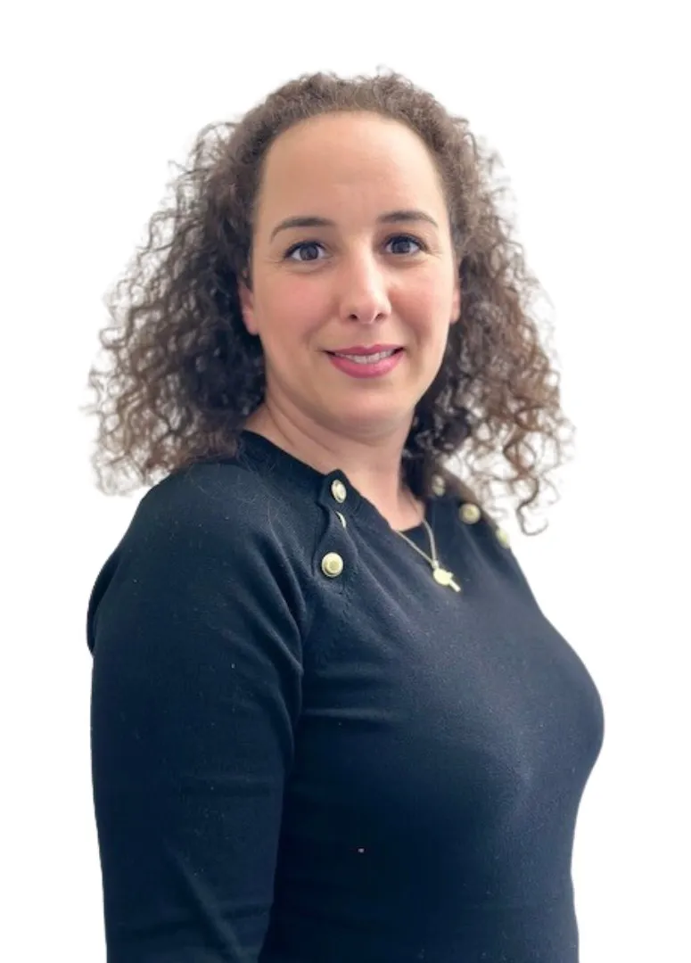 Frau mit lockigen Haaren in schwarzem Oberteil blickt freundlich in die Kamera.